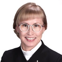 Kirkkoherra Sanna Komulainen hymyilee papin asussaan.