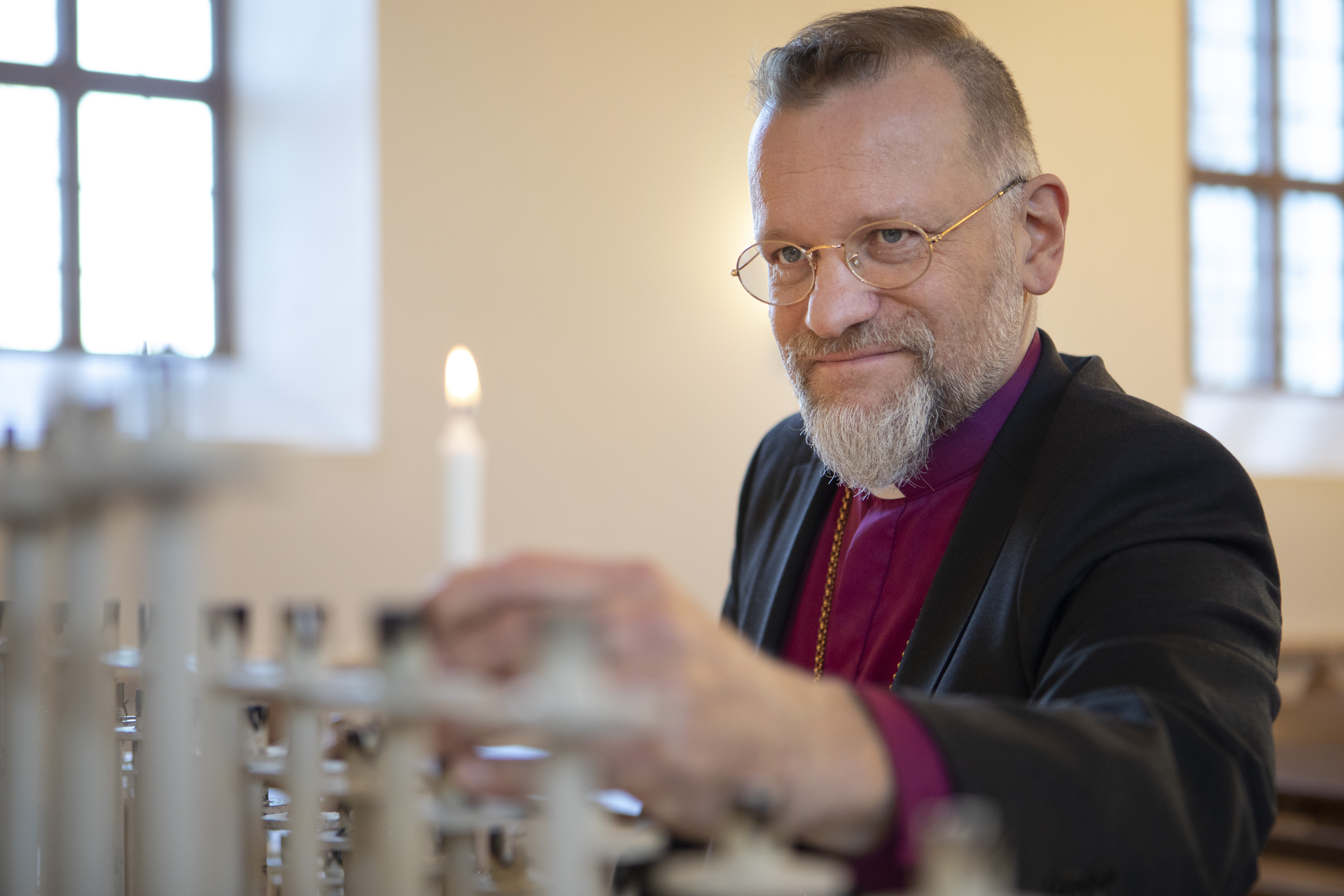 Piispa Jari Jolkkonen sytyttämässä yhtä valkeaa kynttilää.