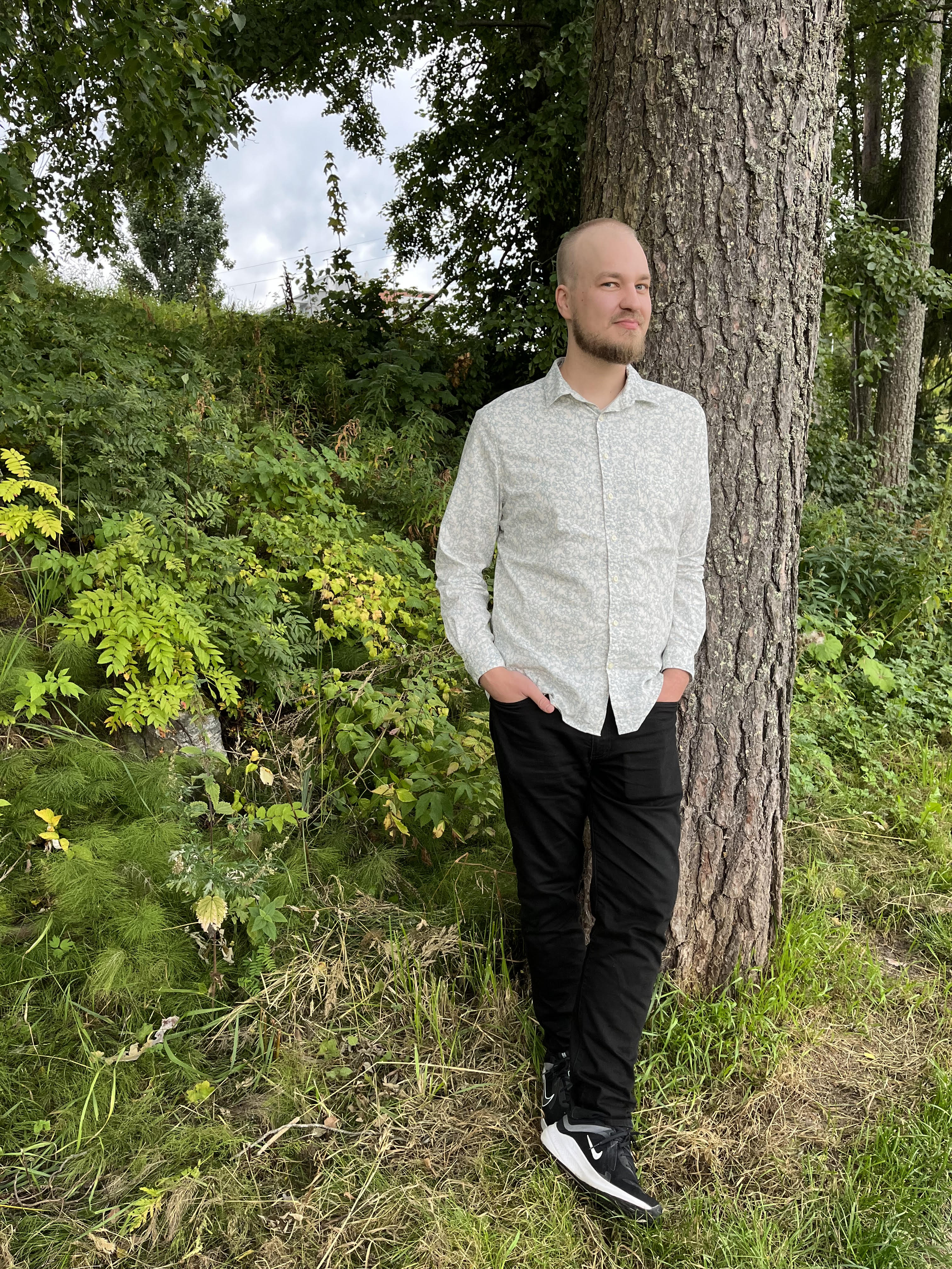 Markus Finnilä nojaa rennosti puun kylkeen kädet taskussa.