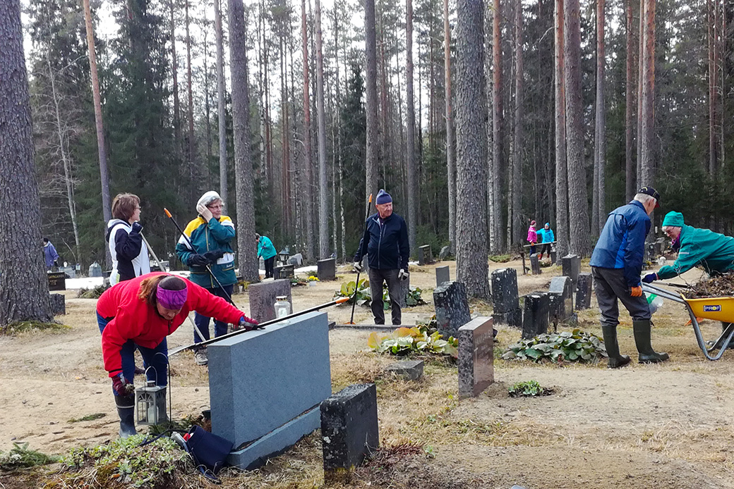 Ihmisiä hautausmaan siivoustalkoissa.