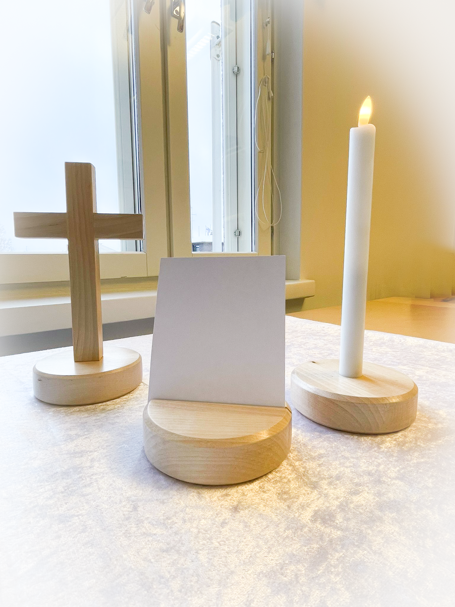 Puinen risti, valokuvapidike ja kynttilänjalka, jossa led-kynttilä.