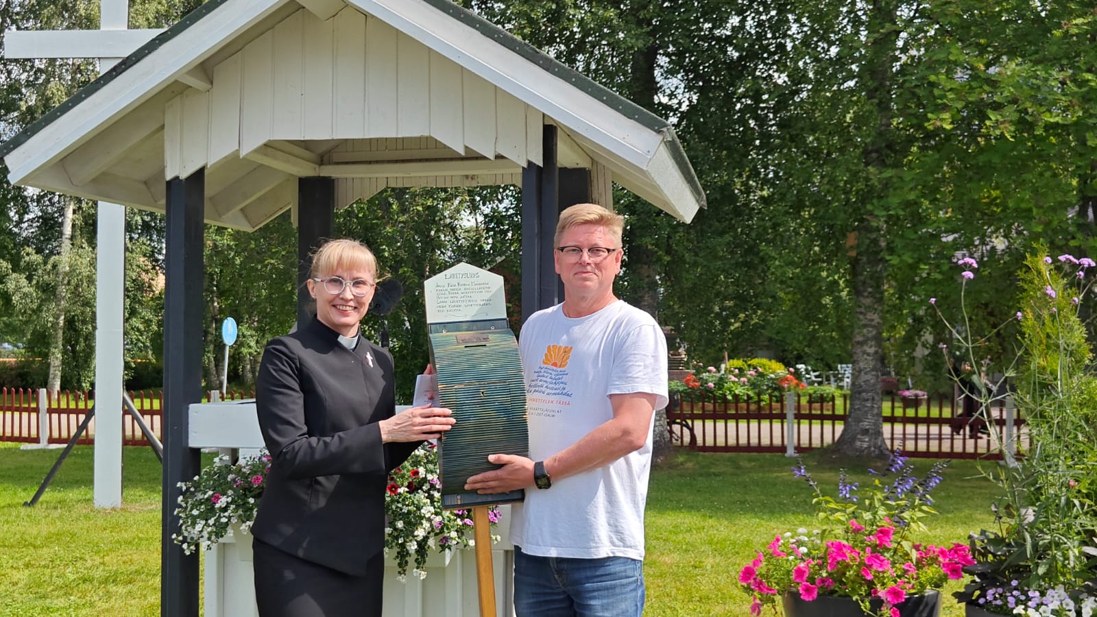 Nainen ja mies pitelevät herättäjäjuhlien puista lähetyslipasta käsissään.