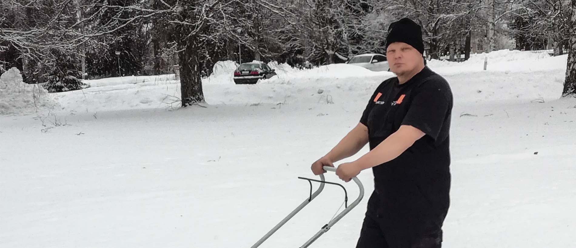 Kalle seisoo lumihangessa ruohonleikkurin kanssa t-paitasillaan.